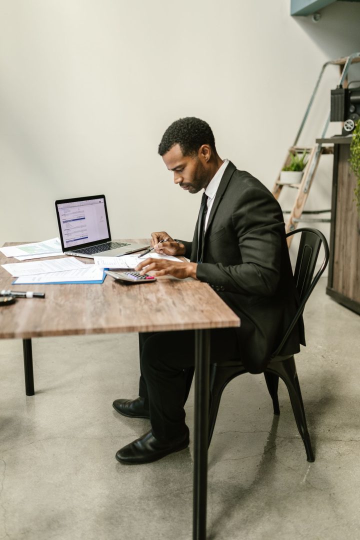 Accountant in a suit working with a calculator and laptop at a desk