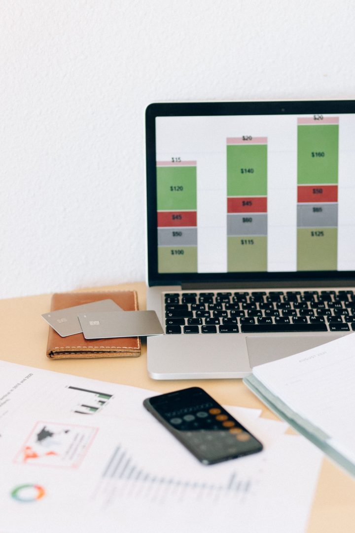 Laptop showing a financial bar chart next to a wallet, cards, and a phone calculator
